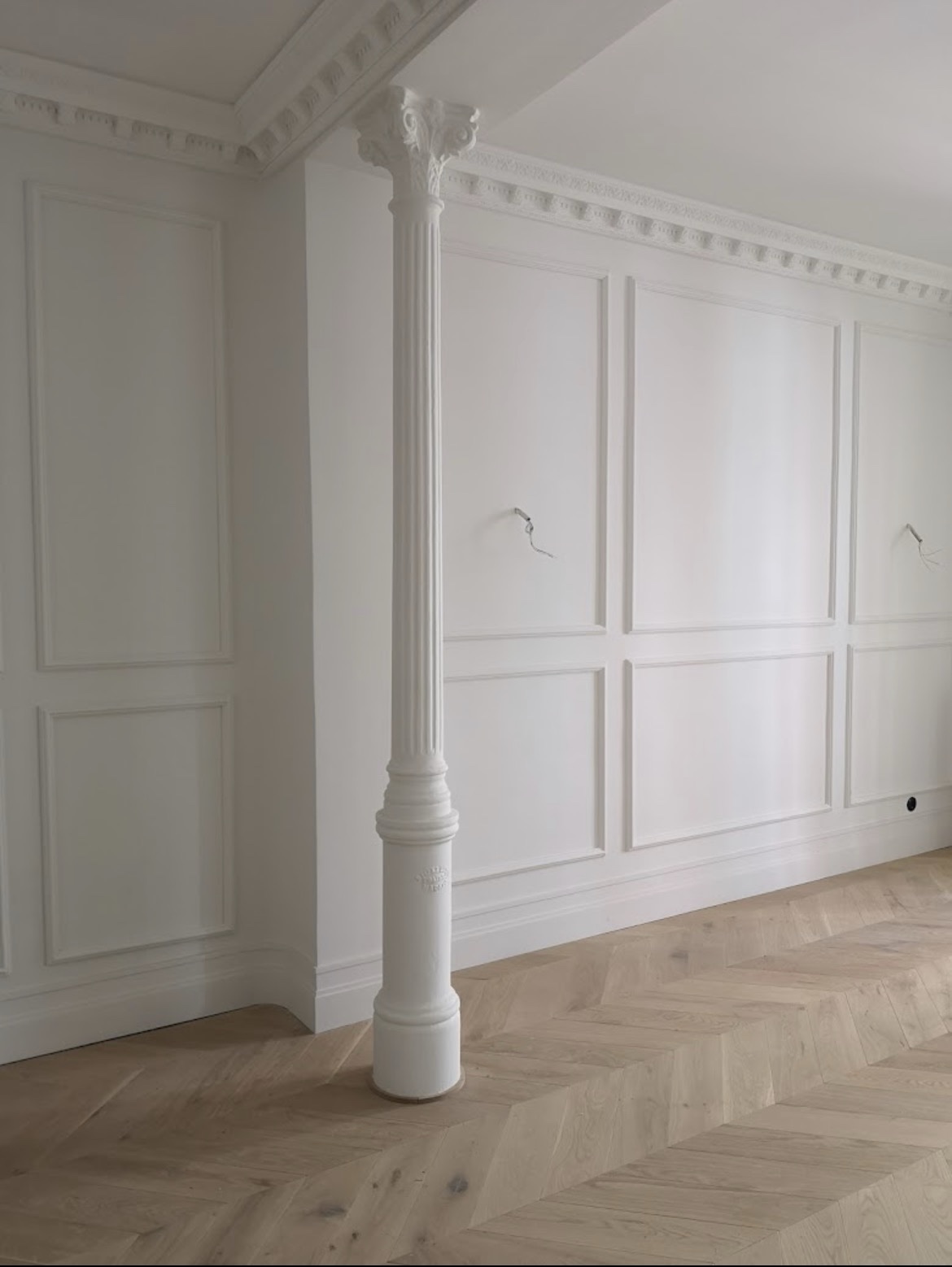 Salón clásico con molduras blancas y columna decorativa